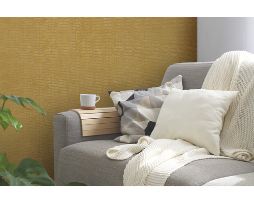 Szene mit gemusterter Tapete, Couch, Kissen, Decke und Beistelltisch