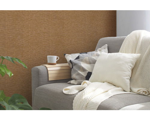 Wohnzimmer mit brauner Struktur-Tapete, Sofa, Kissen und Pflanze