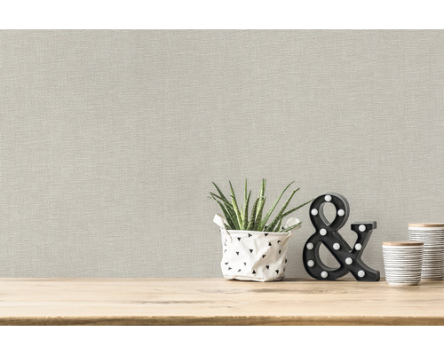 Beige Tapete mit Pflanzenmotiv und dekorativen Elementen auf einem Holztisch