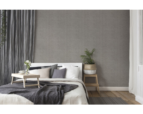 Schlafzimmer mit Bett, Nachttisch und grauer Tapete