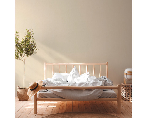 Helles Schlafzimmer mit Holzbett, Zimmerpflanze und Strohhut