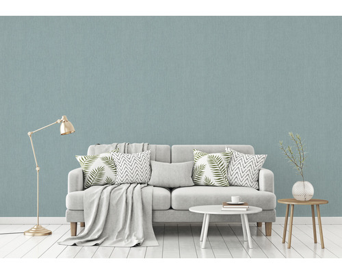 Wohnzimmer mit hellblauer Struktur-Tapete, Sofa, Tisch und Stehlampe.