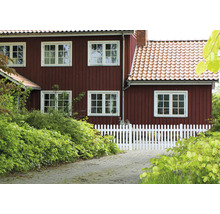 Landhaus mit Holzwänden und weißem Lattenzaun