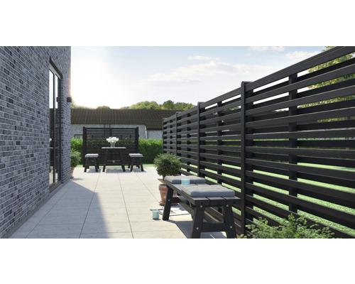 Terrasse mit Holzzaun, Sitzbank und Tischgruppe im Garten.