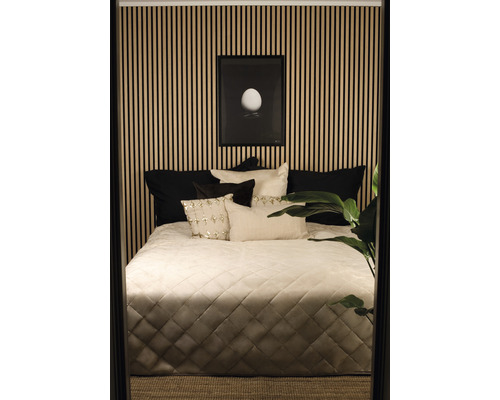 Schlafzimmer mit Bett, Kissen, Tagesdecke und Wandpaneelen
