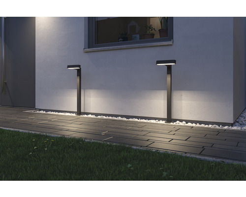 Zwei Außenleuchten beleuchten einen Gehweg vor einem Haus.