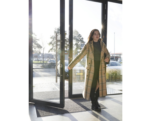 Eingangsbereich mit Fußmatte und einer Frau, die eine Tür öffnet