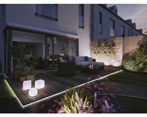 Terrasse mit Gartenmöbeln, Beleuchtung und Pflanzen in der Dämmerung