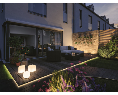 Beleuchtete Terrasse mit Gartenmöbeln, Pflanzgefäßen und dekorativer Beleuchtung.