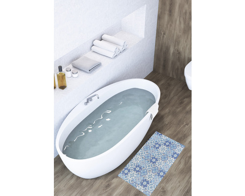 Badezimmer mit freistehender Badewanne, Handtüchern und gemusterter Badematte auf Holzboden