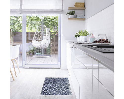 Helle Küche mit Fliesendekor Matte auf dem Boden, Hängekorbsessel im Hintergrund.