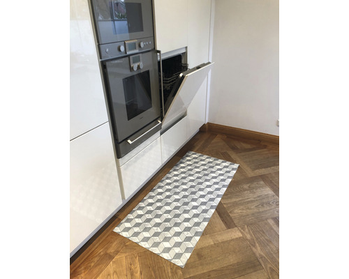 Küche mit Einbaugeräten und einem rechteckigen Teppich mit Würfelmuster auf Holzboden