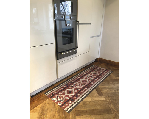 Küche mit Einbaubackofen und gemustertem Läufer auf Holzboden