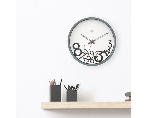 Wanduhr mit Zahlenmuster über einem Regal mit Stifthaltern