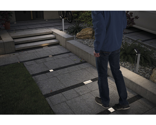 Beleuchteter Gartenweg mit Pflastersteinen und einem Mann