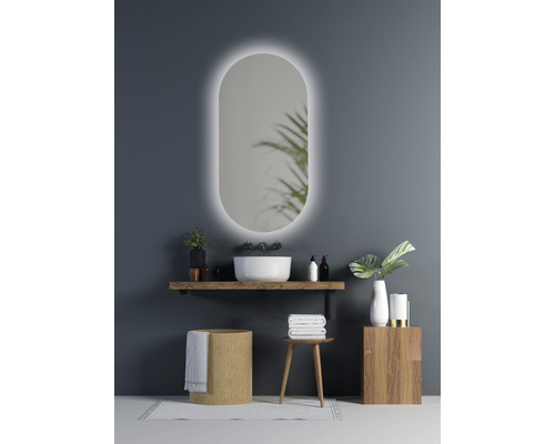 Modernes Badezimmer mit ovalem Spiegel und Beleuchtung, Waschtisch mit Aufsatzwaschbecken und Holzelementen für ein helles, organisiertes Ambiente.