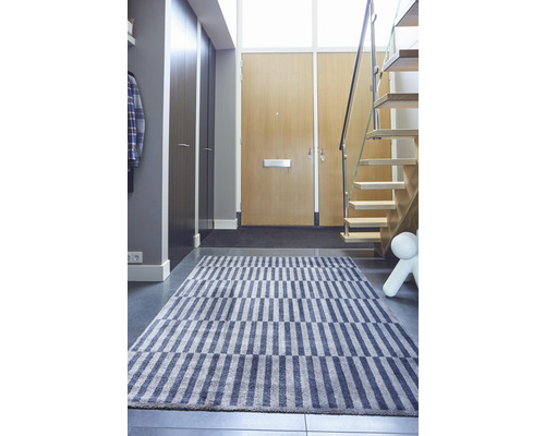 Flur mit gestreiftem Teppich, Treppe und Garderobe.