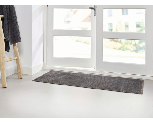 Graue Fußmatte vor einer weißen Tür mit Fenster