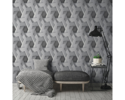 Wohnzimmer mit einer Wandtapete mit geometrischem 3D-Effekt, einem Sessel, einem Hocker und einer Stehlampe.