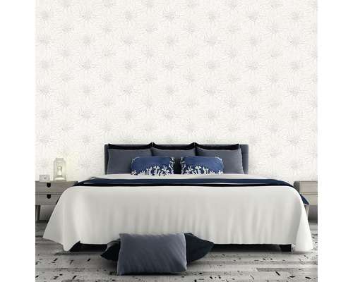Schlafzimmer mit floral gemusterter Tapete, Bett und Nachttischen.
