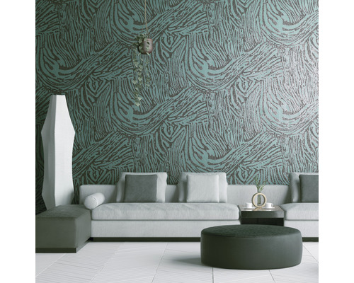 Wohnzimmer mit Sofa, Hocker und einer Wand mit gemusterter Tapete.