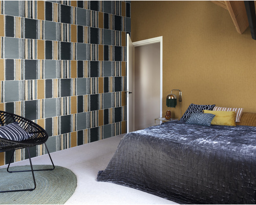 Schlafzimmer mit gemusterter Tapete, Bett und Sessel