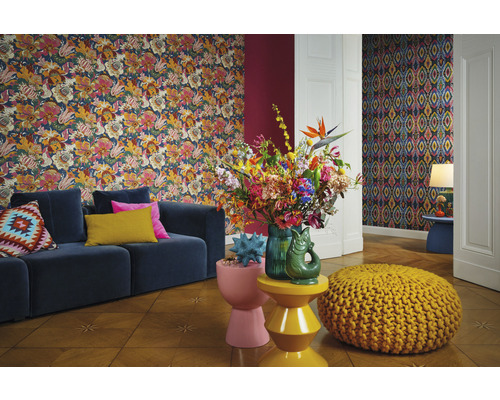 Wohnzimmer mit floraler Tapete, blauem Sofa und bunten Dekorationsgegenständen.