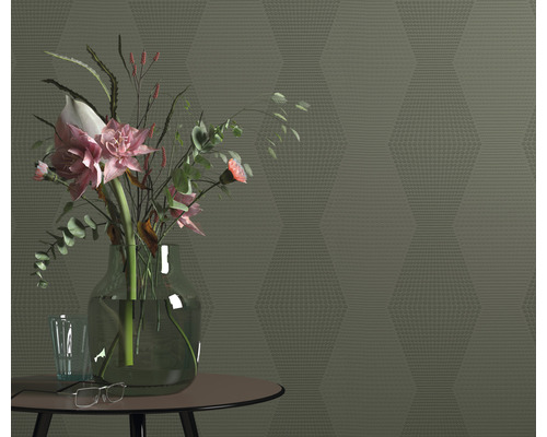 Einrichtungsszene mit einer Vase mit Blumen auf einem Tisch vor einer gemusterten Wand.