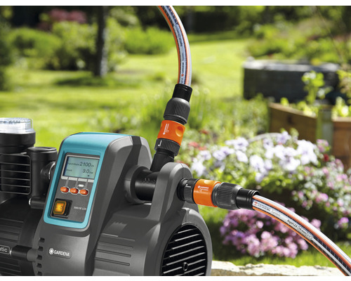 Gartenpumpe mit angeschlossenen Gartenschläuchen im Außenbereich.