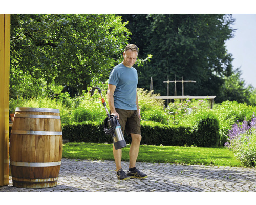 Mann mit elektrischem Fugenkratzer im Garten