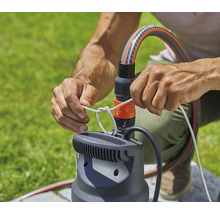 Person befestigt Seil an einer Gartenpumpe mit Schlauchanschluss