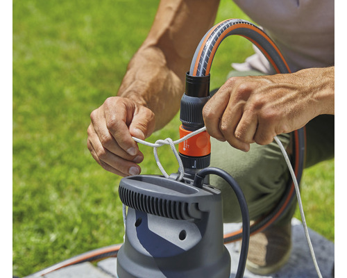 Person befestigt Seil an einer Gartenpumpe mit Schlauchanschluss