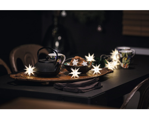 Dekorativer Tisch mit Teekanne, Tassen, Gebäck und Sternenlichterkette