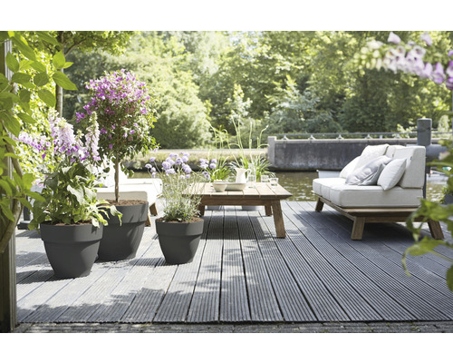 Terrasse mit Pflanzkübeln, Holztisch und Sitzgelegenheiten im Garten