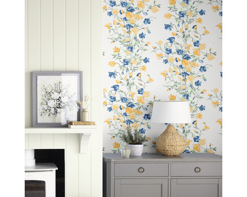 Dekoratives Interieur mit Tapete mit Blumenmuster, Kommode, Lampe und Kamin.