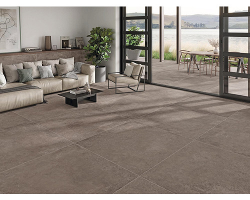 Wohnraum mit Fliesenboden, Sofa, Tisch, Pflanze und Blick auf eine Terrasse mit Esstisch