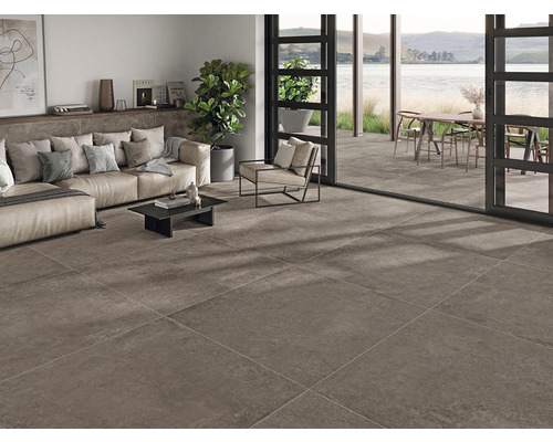 Wohnzimmer mit Bodenfliesen, Sofa, Sessel und Blick auf den Außenbereich mit Terrasse