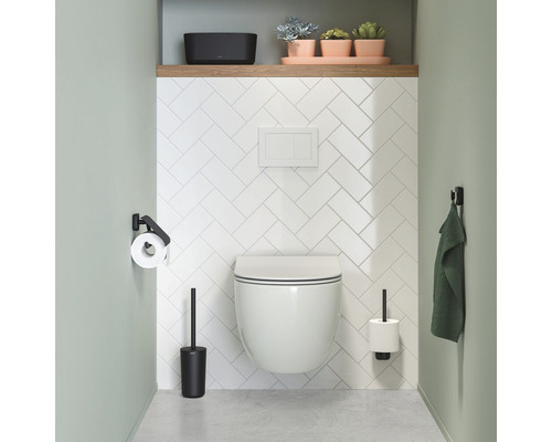 Modernes Badezimmer mit wandhängendem WC, Toilettenbürste, Toilettenpapierhalter, Handtuch und Pflanzen