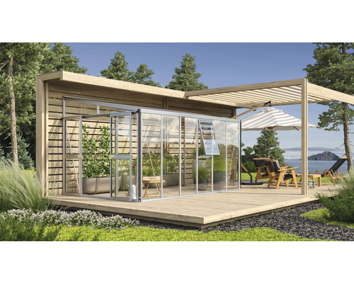 Außenansicht eines Gewächshauses mit Holzterrasse und Gartenmöbeln.