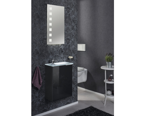 Badezimmer mit Waschtisch, Spiegel und Toilette an dunkler Wand