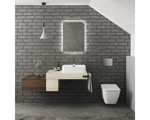 Modernes Badezimmer mit Waschbecken, Spiegel mit Beleuchtung und Wandtoilette vor einer Ziegelwand