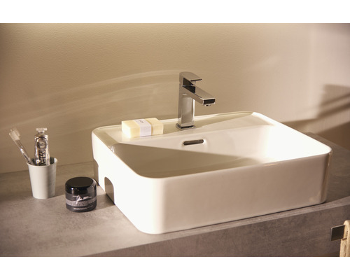 Waschbecken mit Armatur, Seife, Zahnbürste und Kosmetikprodukten auf einem Waschtisch