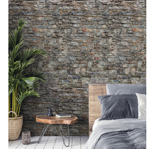 Wohnraum mit einer Tapete in Steinoptik, einem Nachttisch und einem Bett.