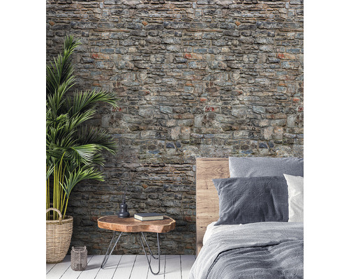 Wohnraum mit einer Tapete in Steinoptik, einem Nachttisch und einem Bett.