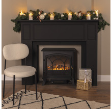 Dekorativer Kamin mit Dekoration, Geschenken, Sessel und Teppich in einem Wohnzimmer