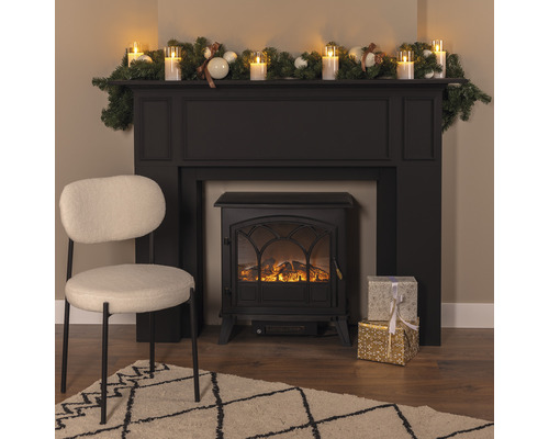 Dekorativer Kamin mit Dekoration, Geschenken, Sessel und Teppich in einem Wohnzimmer