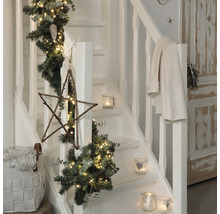 Dekorierte Treppe mit Tannengirlande, Lichtern, Holzstern und Windlichtern für die Weihnachtszeit