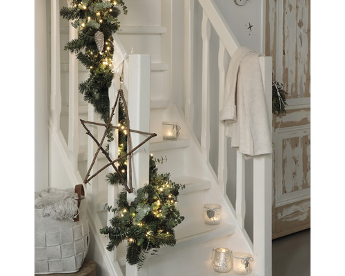 Dekorierte Treppe mit Tannengirlande, Lichtern, Holzstern und Windlichtern für die Weihnachtszeit