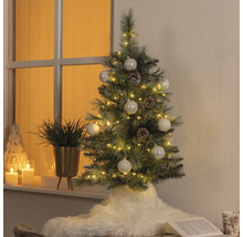Dekorierter künstlicher Weihnachtsbaum mit Beleuchtung, Kugeln und Tannenzapfen in Wohnraum