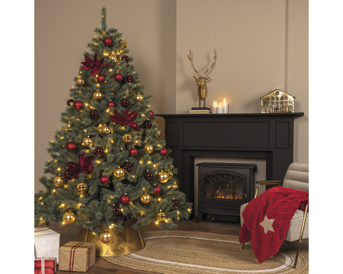 Weihnachtsbaum mit rotem und goldenem Weihnachtsschmuck in einem Wohnzimmer mit Kamin